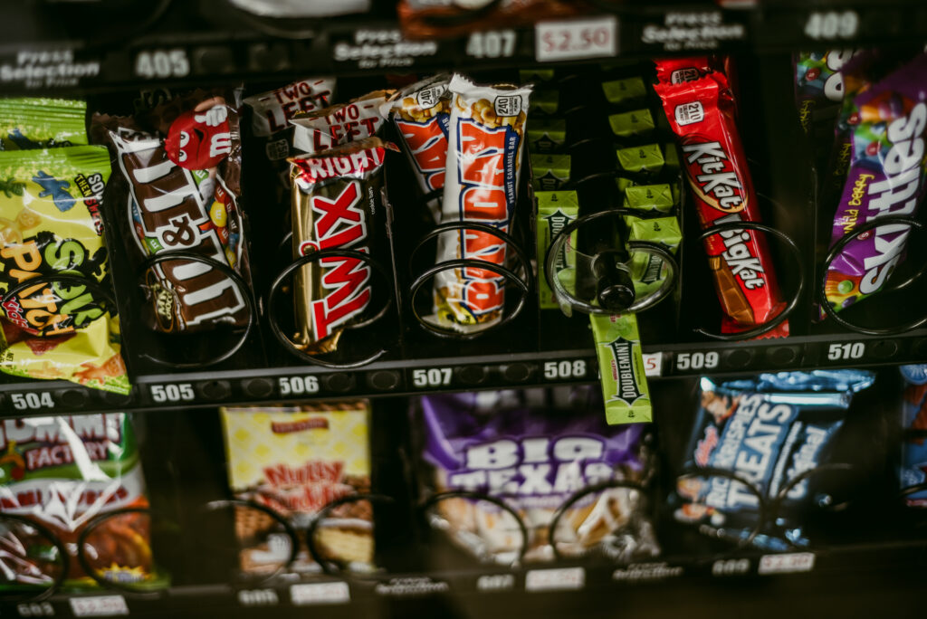 Distributeur automatique de snacks avec plusieurs rangées de barres chocolatées et bonbons emballés